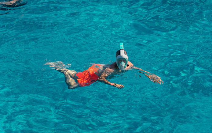 Snorkeler in clear blue water at Cala Bassa beach, Ibiza, Spain.