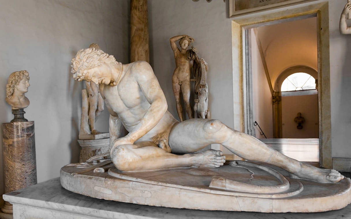 Dying Gaul statue in Capitoline Museum, Rome, depicting a wounded warrior in a classical setting.
