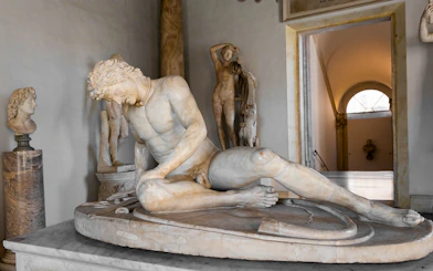 Dying Gaul statue in Capitoline Museum, Rome, depicting a wounded warrior in a classical setting.