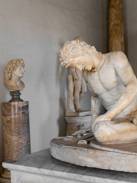 Dying Gaul statue in Capitoline Museum, Rome, depicting a wounded warrior in a classical setting.