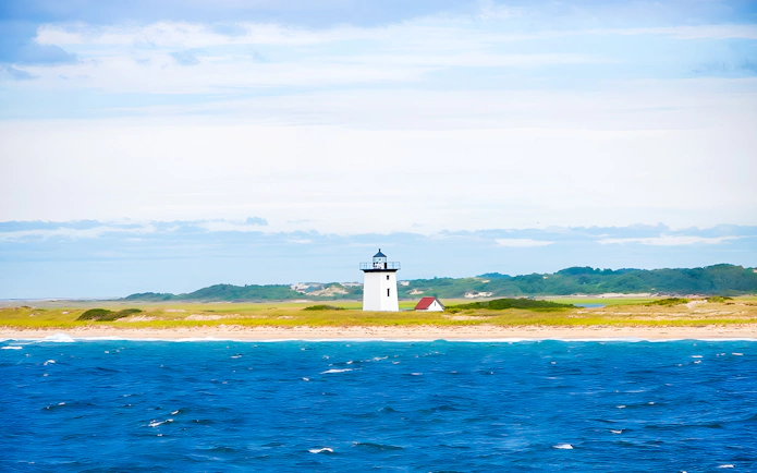 Long Point Lighthouse on sandy shore with ocean in Provincetown, Massachusetts.