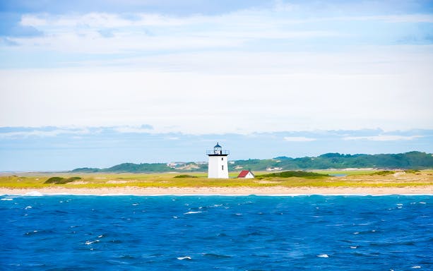 Long Point Lighthouse on sandy shore with ocean in Provincetown, Massachusetts.