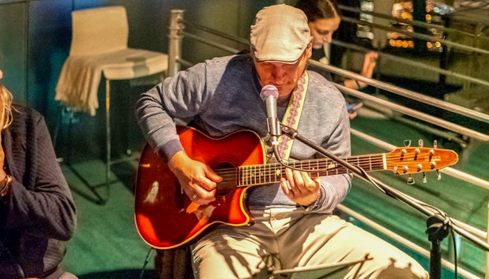 An old man playing guitar in open stage at Tivoli during a Live Music Session