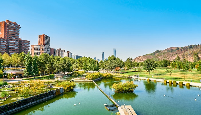 Parque Bicentenario in Chile with pond, trees, and city skyline in the background.