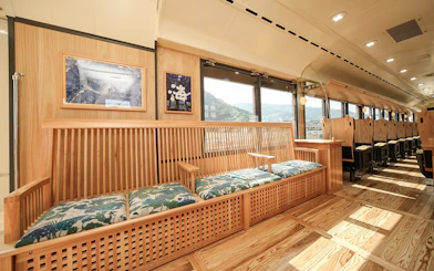 Scenic train interior with wooden seating and large windows in Kyushu, Japan.