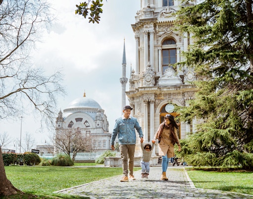 Family exploring Dolmabahce Palace courtyard, Istanbul, Turkey.