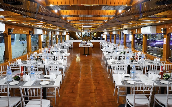 Dining setup on a dhow cruise in Dubai Marina with tables and chairs arranged for dinner.
