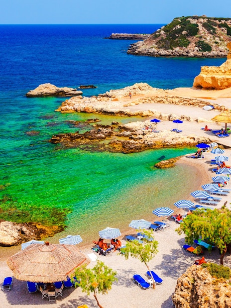 Beach with umbrellas and clear waters on Charaki Island, Rhodes, Greece.