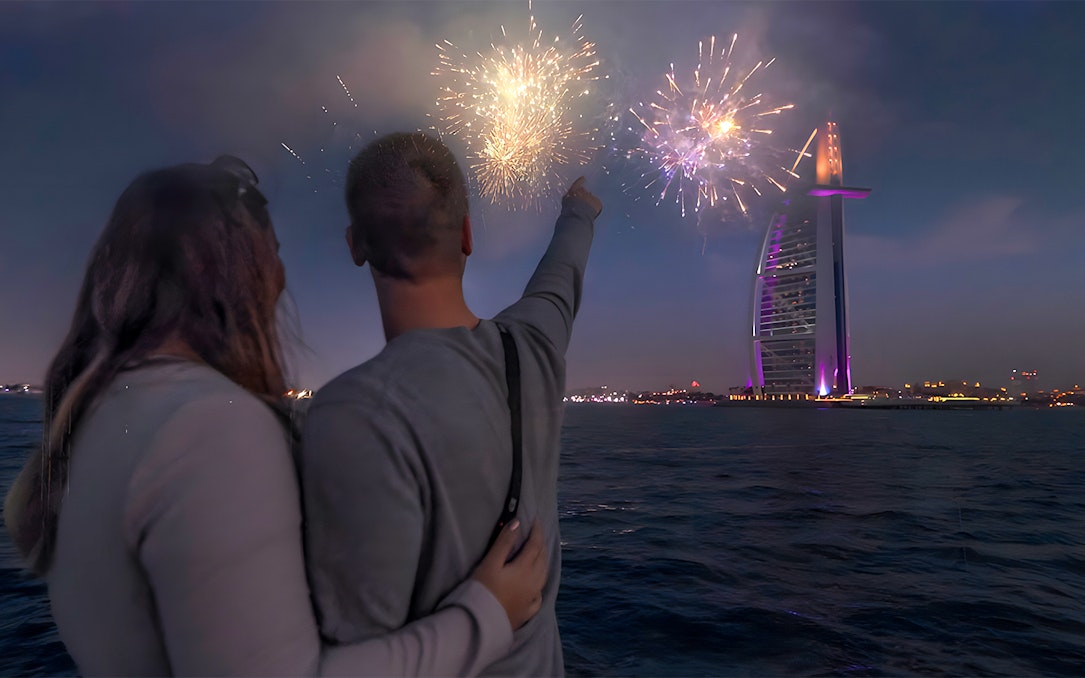 Couple on speedboat watching Burj Al Arab fireworks during New Year Eve in Dubai.