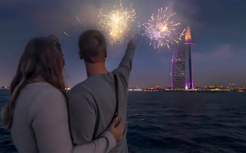 Couple on speedboat watching Burj Al Arab fireworks during New Year Eve in Dubai.