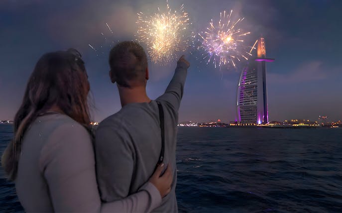 Couple on speedboat watching Burj Al Arab fireworks during New Year Eve in Dubai.