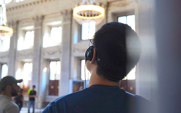 Person wearing headphones inside a historic building on an Amsterdam audio tour.