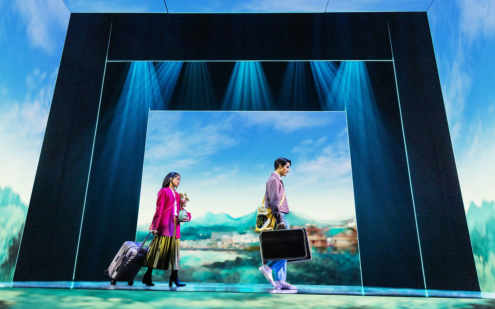 Actors on stage during Maybe Happy Ending Broadway show, carrying suitcases with scenic backdrop.