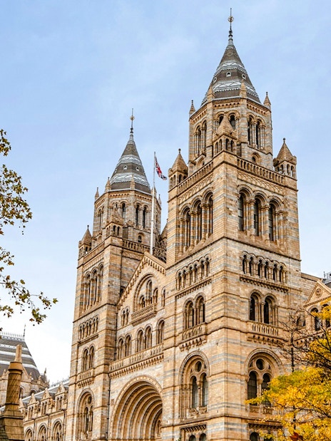 Natural History Museum exterior with twin towers and autumn trees in London.