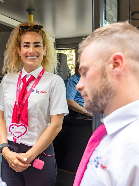 Open bus crew members welcoming passengers onboard.