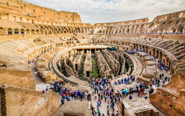 Colosseum interior with tourists exploring the ancient gladiator arena in Rome.