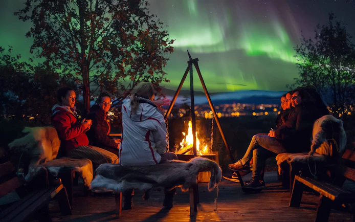 People gathered around a campfire under the Northern Lights in Tromso.