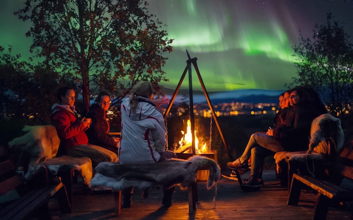 People gathered around a campfire under the Northern Lights in Tromso.