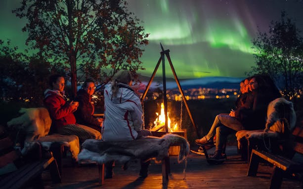 People gathered around a campfire under the Northern Lights in Tromso.