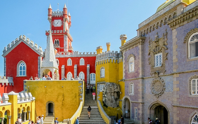 Pena Palace in Sintra, Portugal, with colorful architecture and tourists exploring.