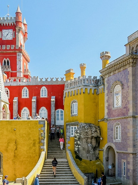 Pena Palace in Sintra, Portugal, with colorful architecture and tourists exploring.