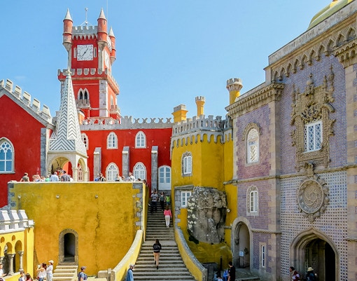 Pena Palace in Sintra, Portugal, with colorful architecture and tourists exploring.