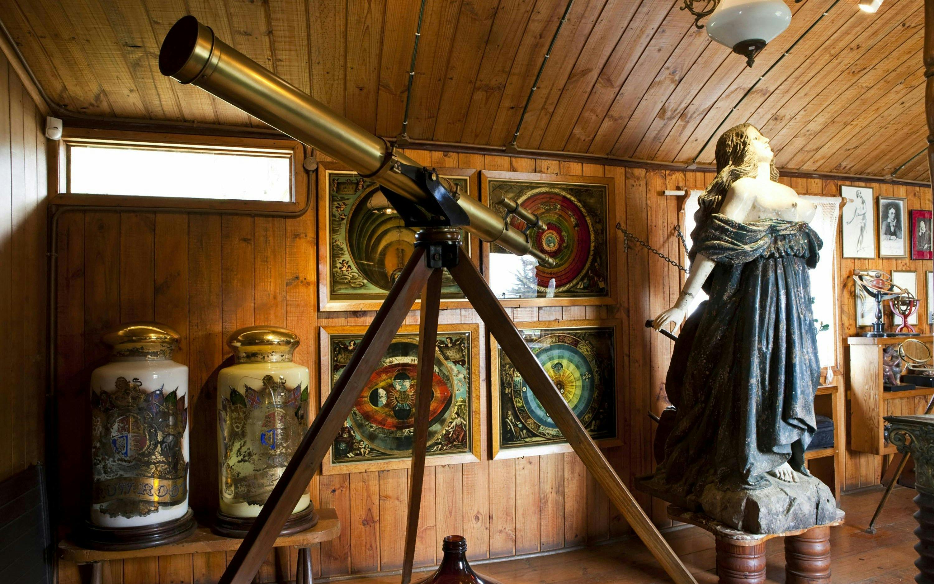 Telescope inside Pablo Neruda Museum at Isla Negra, Chile, surrounded by art and sculptures.