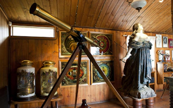 Telescope inside Pablo Neruda Museum at Isla Negra, Chile, surrounded by art and sculptures.