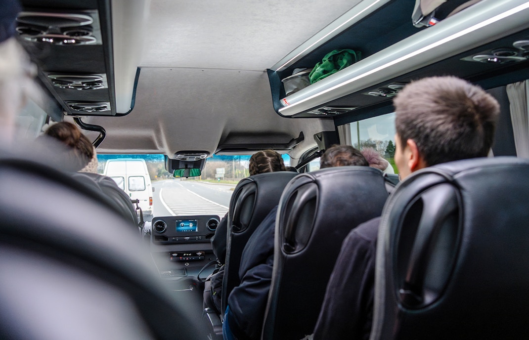 Group of happy passengers in a travel bus with views of the Grand Canyon West Rim.