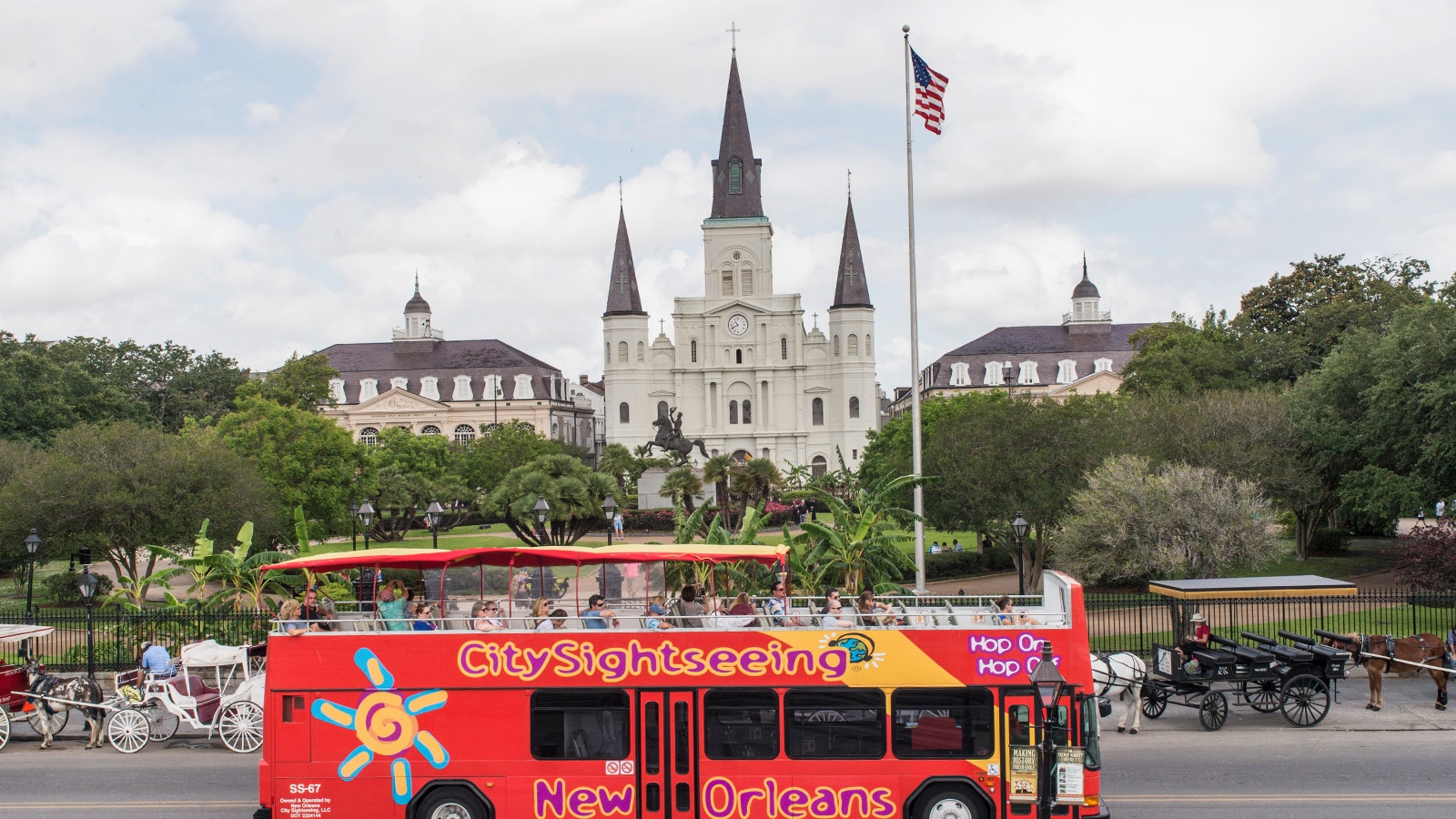 Red double-decker bus on a City Sightseeing tour passing by historic buildings in New Orleans.