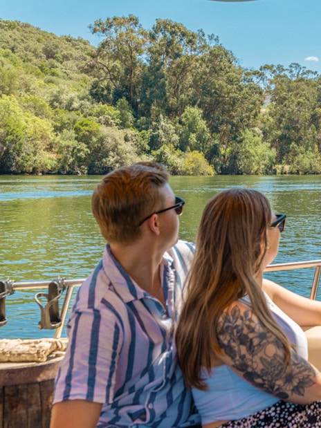 Tourists enjoying a boat ride on the Douro River with scenic vineyard views.