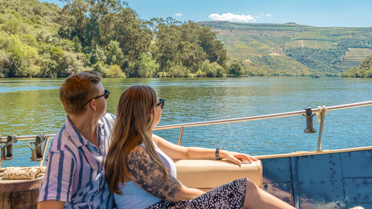 Tourists enjoying a boat ride on the Douro River with scenic vineyard views.