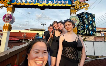 Visitors smiling under the Amphawa Floating Market sign during a private shore excursion from Laem Chabang, Pattaya.