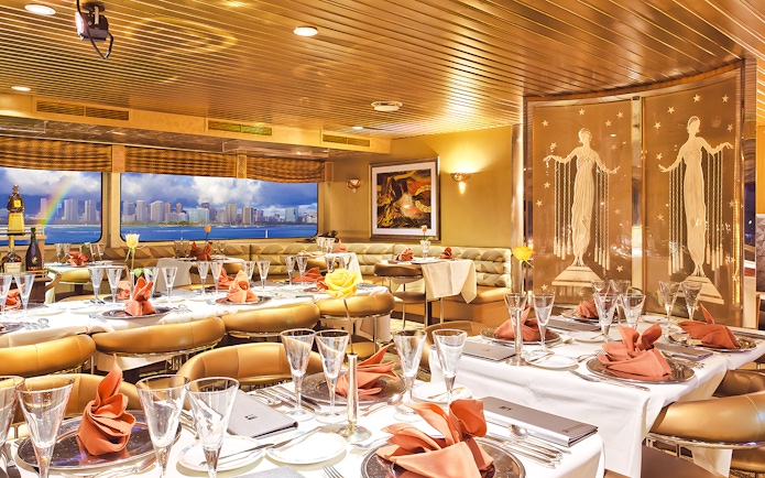 Dining area inside Nova Five Star 2 with elegant table settings and city skyline view.