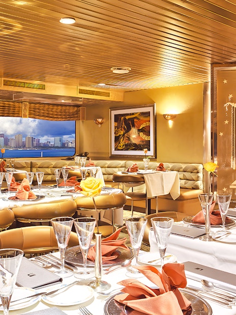 Dining area inside Nova Five Star 2 with elegant table settings and city skyline view.