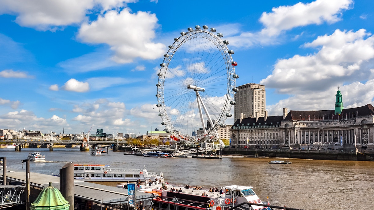 London Eye on the Thames River with nearby historic buildings, UK.