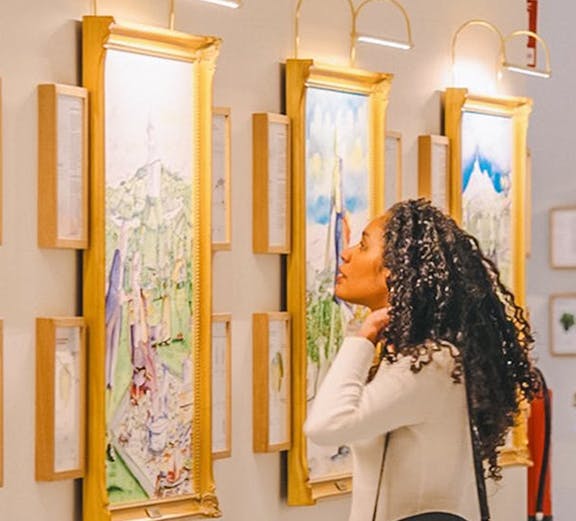 Visitor admiring wine-themed artwork in a gallery during The Wine Experience tour.