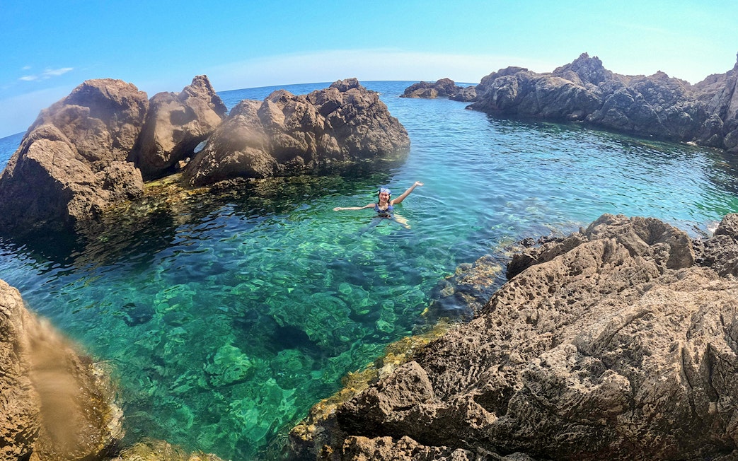 Swimmer enjoying clear waters near rocky cliffs on Dubrovnik boat tour.