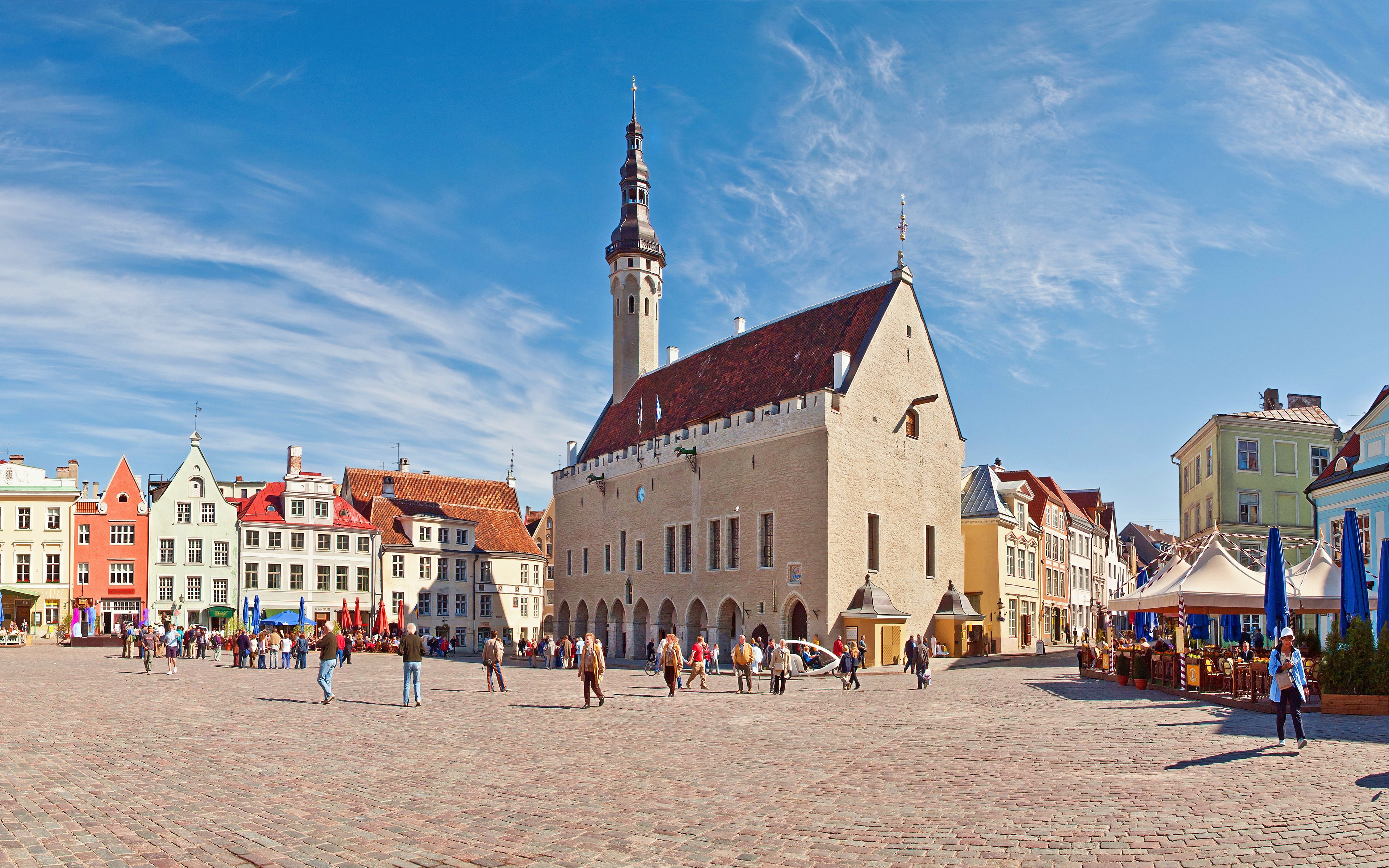 Tallinn Town Hall and Town Hall Square with colorful buildings and people walking.