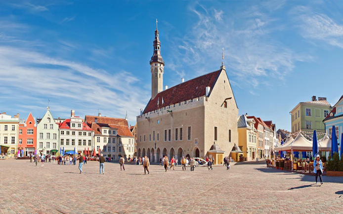 Tallinn Town Hall and Town Hall Square with colorful buildings and people walking.