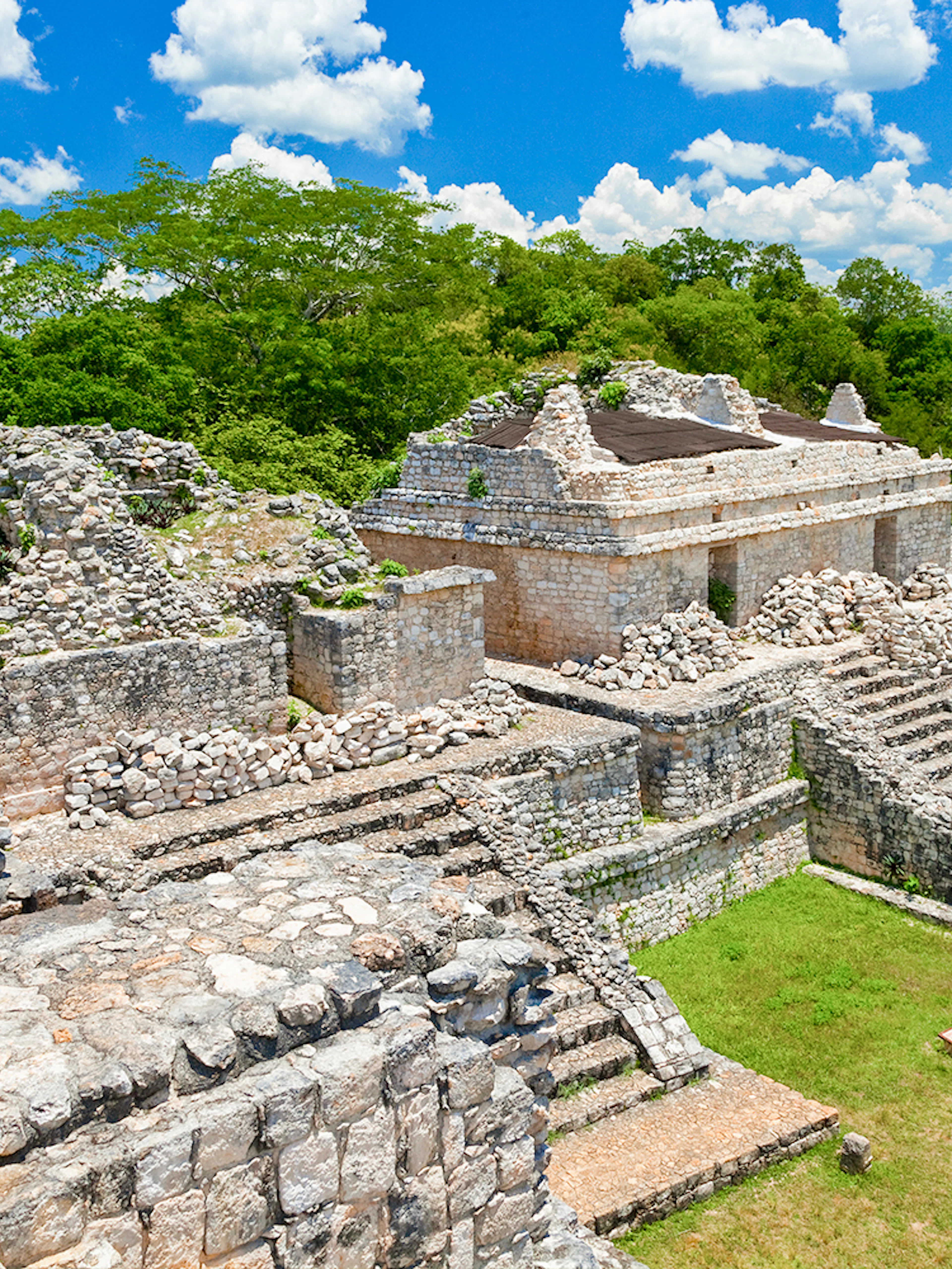 Ek Balam ruins with stone structures and tourists, Yucatan Peninsula, Mexico.