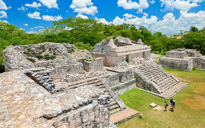 Ek Balam ruins with stone structures and tourists, Yucatan Peninsula, Mexico.