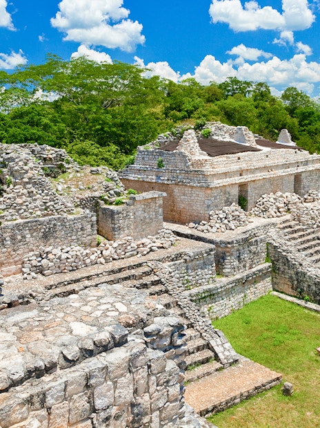 Ek Balam ruins with stone structures and tourists, Yucatan Peninsula, Mexico.