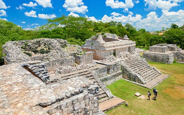 Ek Balam ruins with stone structures and tourists, Yucatan Peninsula, Mexico.