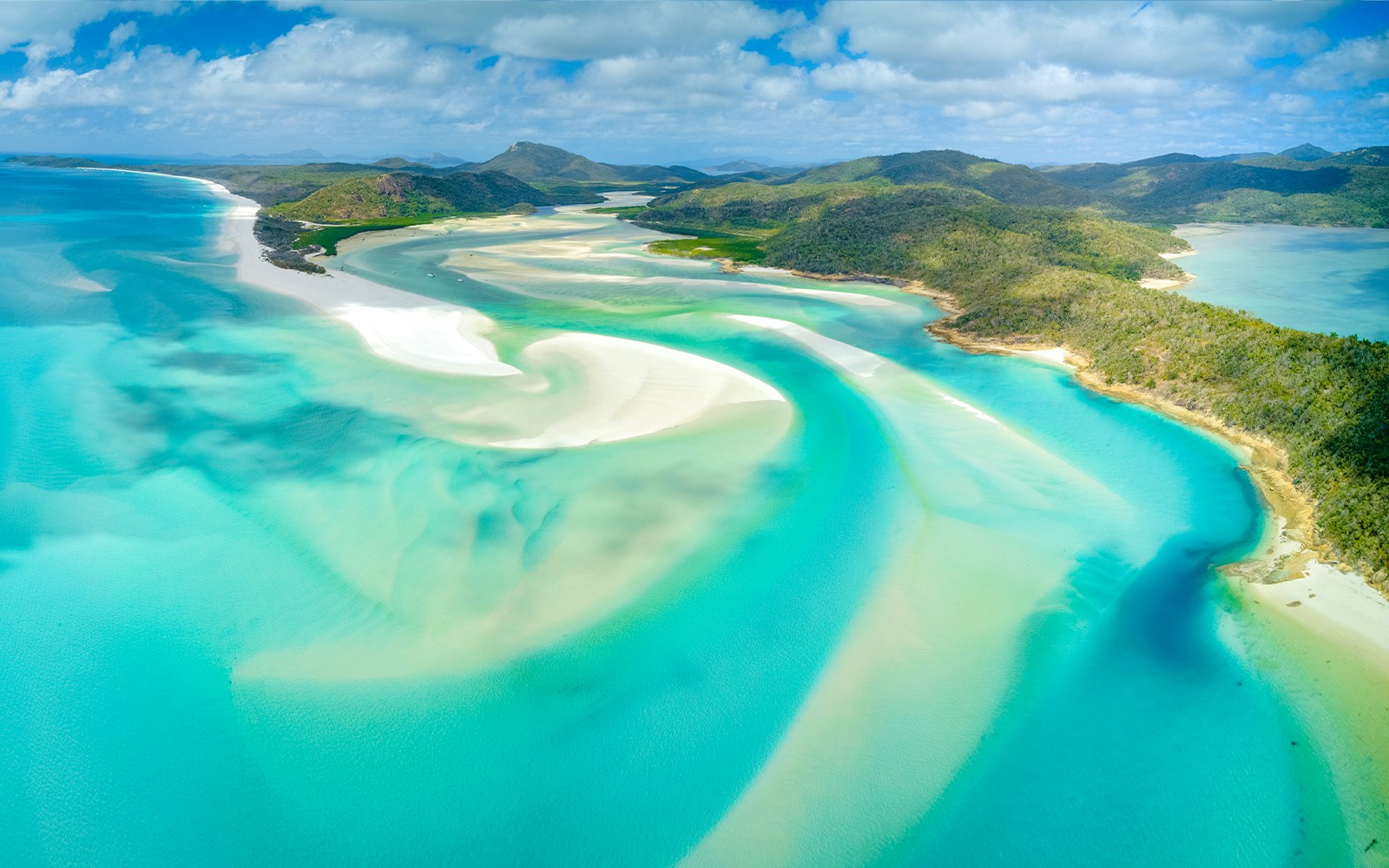Aerial view of swirling turquoise waters and white sands at Whitsunday Islands, Australia.