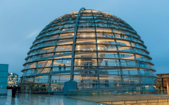 Reichstag Dome in Berlin at dusk, showcasing modern architecture and historical significance.