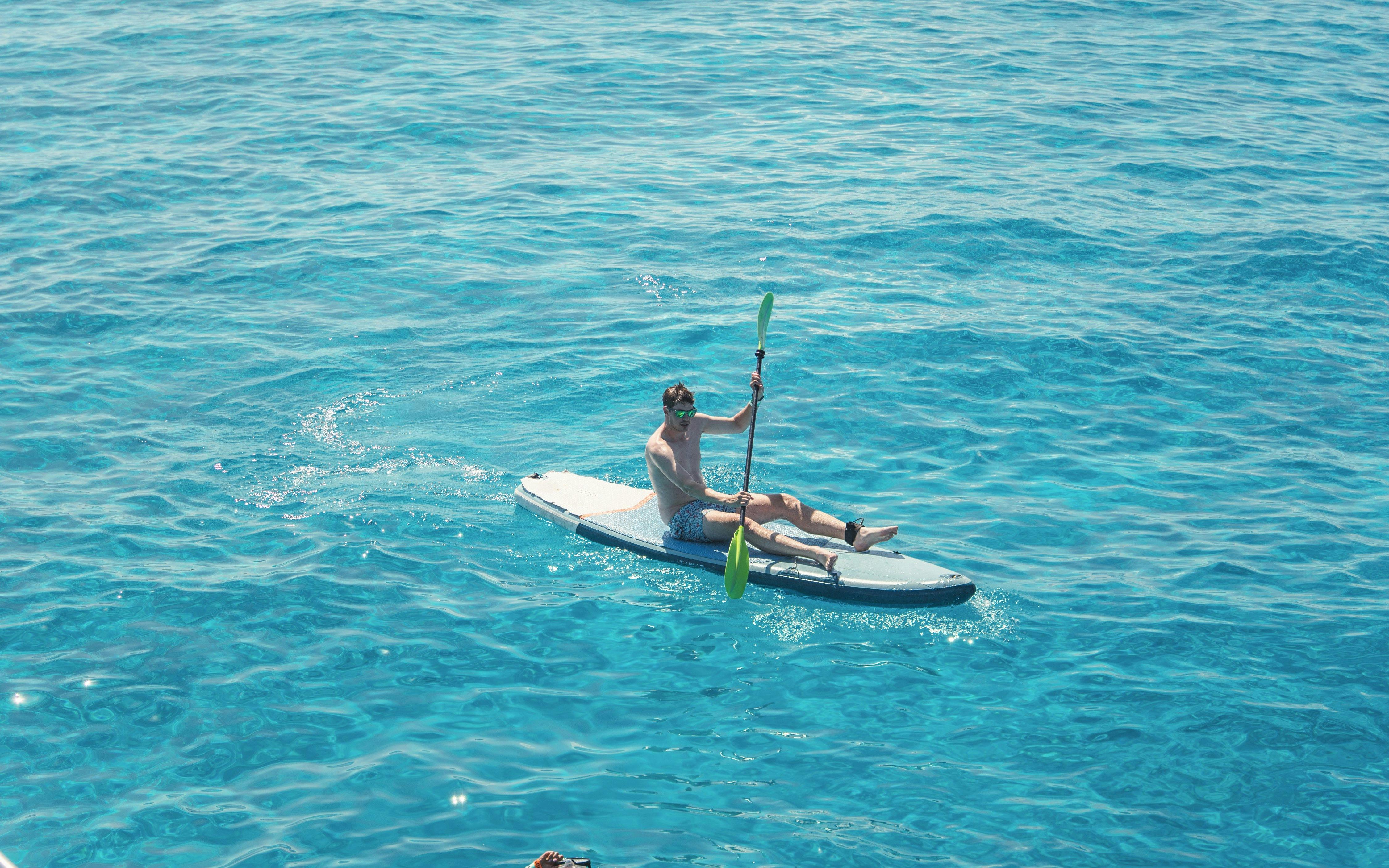 Tourist kayaking on clear waters at Cala Bassa Beach, Ibiza, Spain.