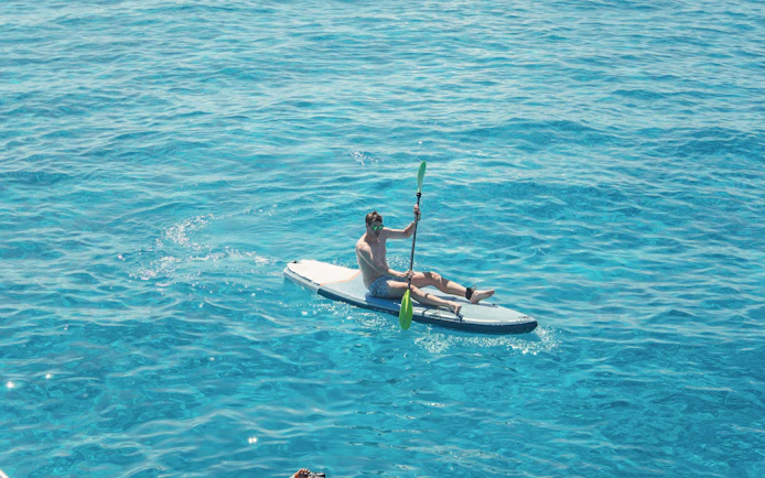 Tourist kayaking on clear waters at Cala Bassa Beach, Ibiza, Spain.