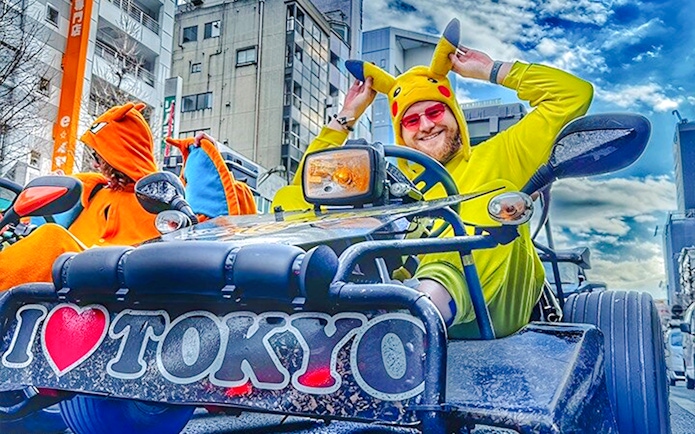 Man in Pikachu costume driving a go-kart in Tokyo street.
