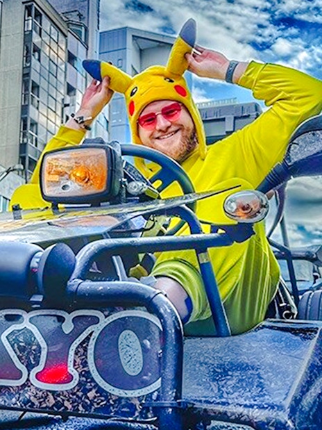 Man in Pikachu costume driving a go-kart in Tokyo street.